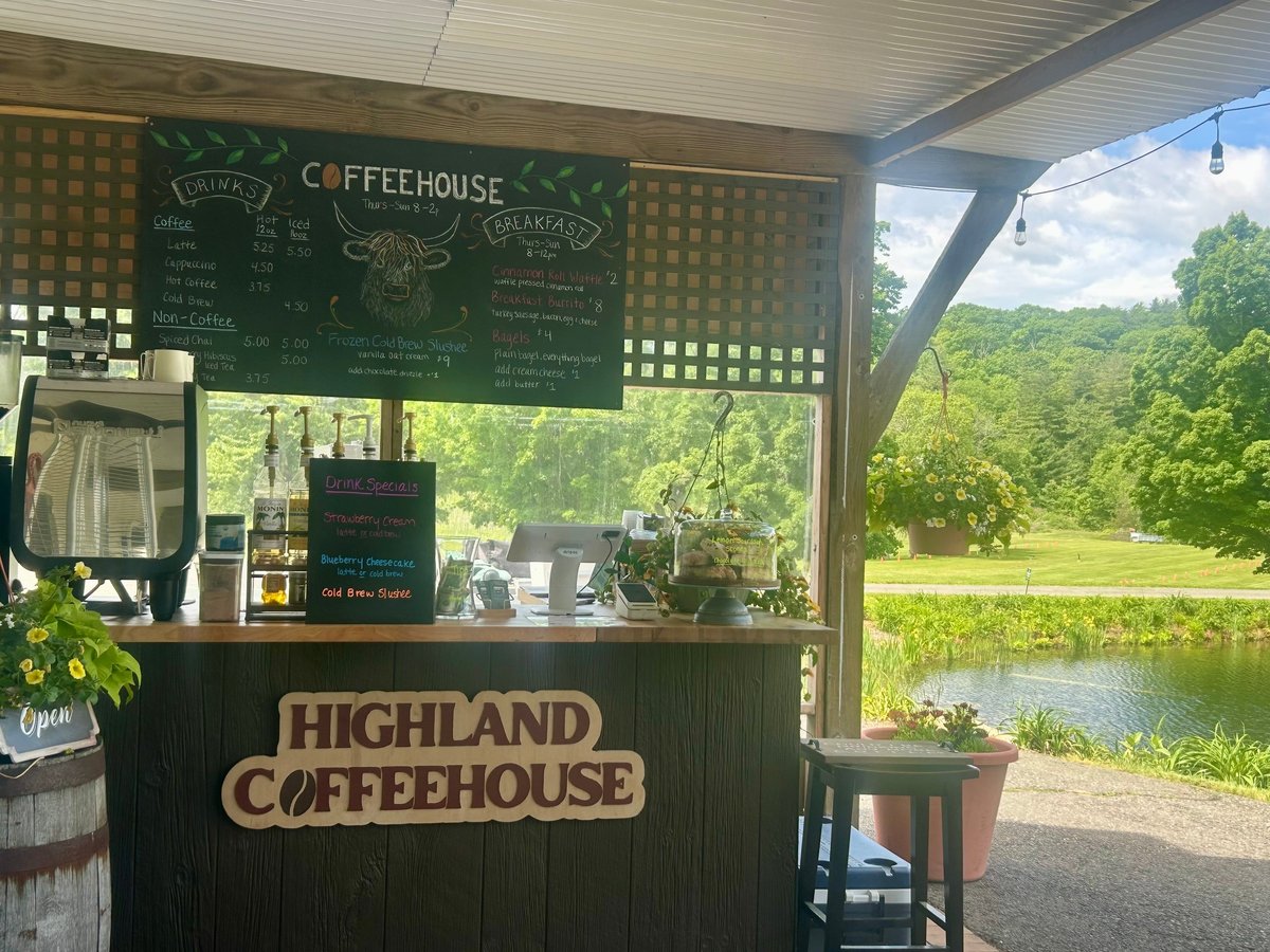 Highland Coffeehouse outdoor counter with green chalkboard menu, overlooking a scenic river and lush trees