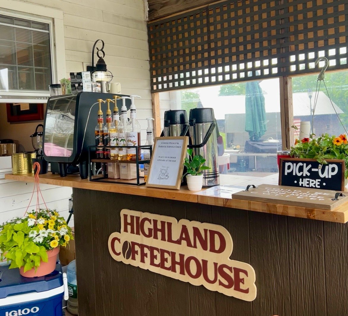 Highland Coffeehouse counter with espresso machine, plants, and pickup sign under covered porch with lattice roof